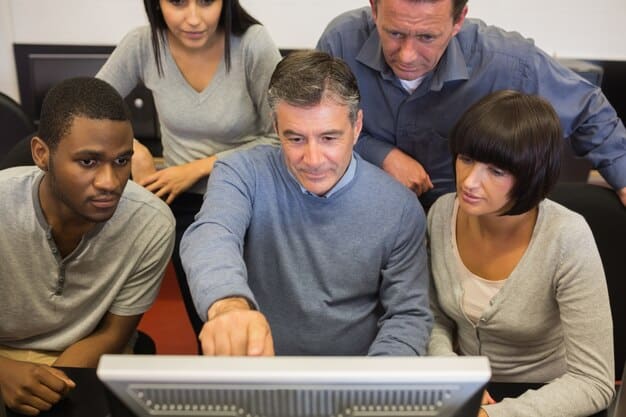 A group of employees participating in a cybersecurity training session. The instructor is pointing at a presentation slide with a warning sign and the words 