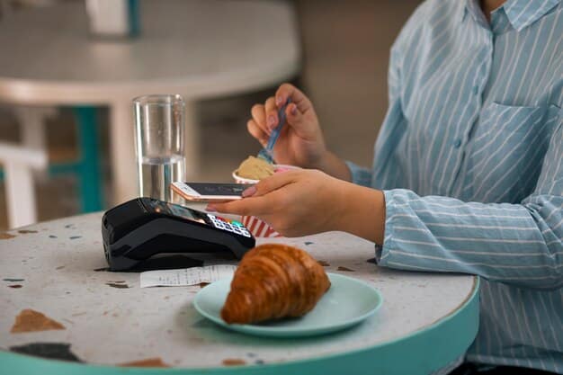 A close-up of a contactless payment card being tapped on a payment terminal. The card features a contactless payment symbol. The background is a cafe counter with coffee cups and pastries.
