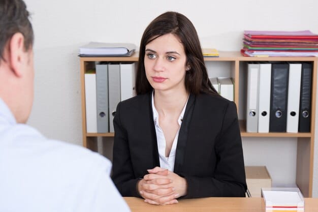 A close-up of an interview setting. The interviewer, a woman in a business suit, is smiling while engaged in a discussion with a candidate. The overall impression is of a welcoming and insightful professional exchange.